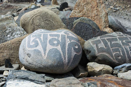 Colored inscriptions on stones in the mountains of Nepal on a Sunny day.