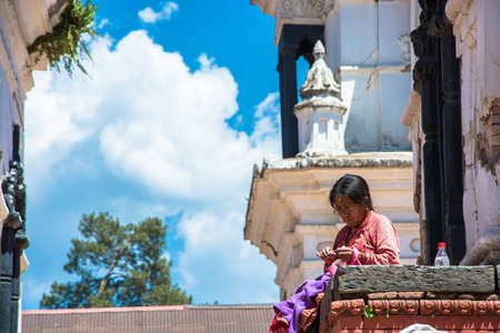 Kathmandu, Nepal - 04/04/2018: an Old woman sewing clothes in the temple complex Pesonalised 13 April 2018, Kathmandu, Nepal.のeditorial素材