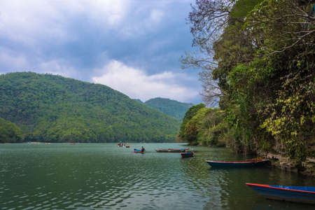 Picturesque Phewa lake with colorful boats on a quiet spring evening in Pokhara, Nepal.のeditorial素材