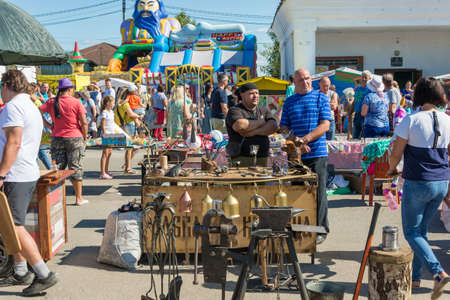 Luh, Ivanovo region, Russia - 08/25/2018: Blacksmith with his products at the regional festival-fair Luk-luchok August 25, 2018 in the city of Luh, Ivanovo region, Russia.のeditorial素材