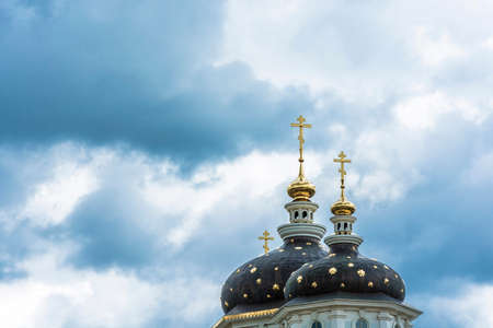 Beautiful church domes with gold crosses against a cloudy sky on a cloudy day.