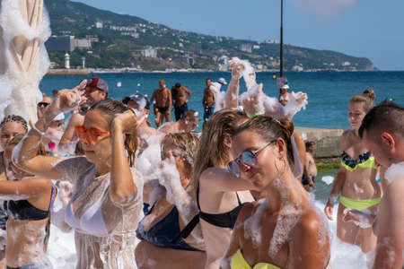 Yalta, Crimea - 07/09/2019: Beautiful girls in snow-white foam on the beach on a sunny day.のeditorial素材