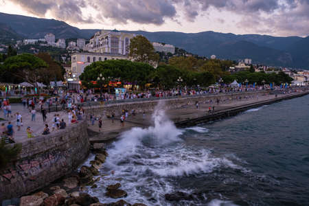 Yalta, Crimea - 09/07/2019: Huge waves break on a stone embankment in the evening.