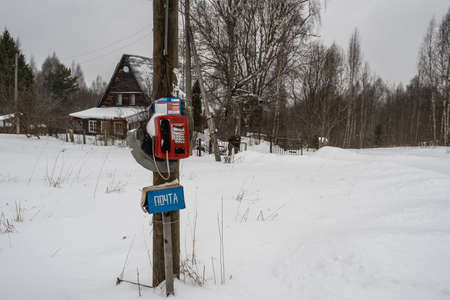 Village Krasnoramenye, Yaroslavl region, Russia. - 11.02.2020: Red telephone set on a wooden pole on a winter day. の写真素材