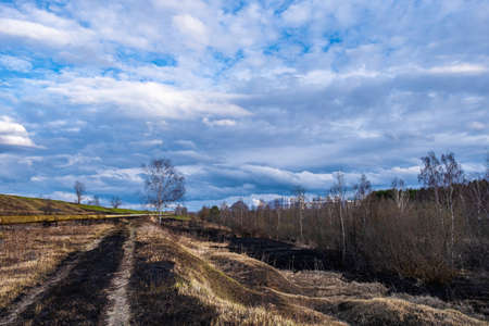The outskirts of the city of Ivanovo with lots of burnt grass last year and a beautiful cloudy sky.