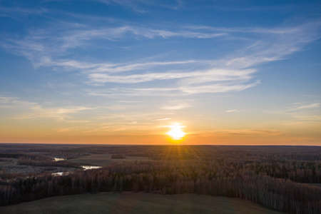 The white disk of the setting sun and the endless fields and forests of Russia, photo taken from a drone.の写真素材