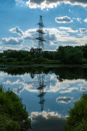 Reflection of power lines and clouds in the water of the Uvod river on a summer day, the city of Ivanovo, Russia.の写真素材