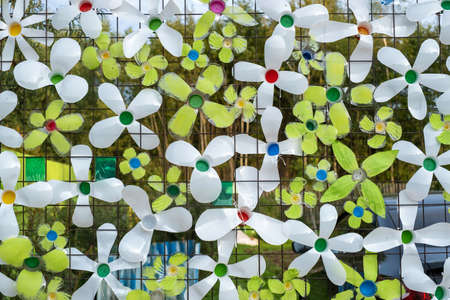 Decoration from multi-colored plastic bottles on a mesh metal fence, close-up photo.の写真素材