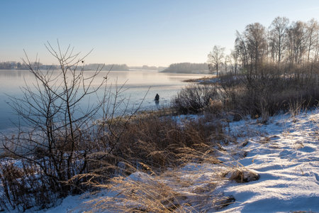 Fisherman on the ice of a big river on a sunny winter day, Russia.の写真素材