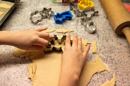 Child shaping and cutting baking cookies for christmas