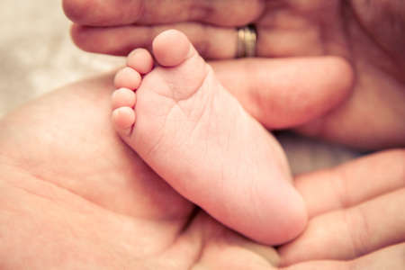 Parents holding the little feet of their newborn baby.の写真素材