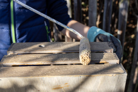a child paints a wooden box with brushes in the garden