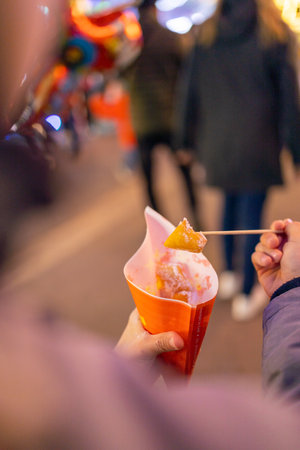 Fresh donuts with icing sugar at the Christmas market are eaten by a little child.
