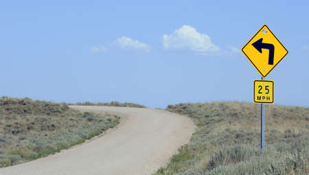 Left turn sign on remote dirt roadの写真素材
