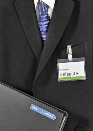 Closeup on male business suit with conference folder and delegate badge. The conference logo has been falsifiedの写真素材