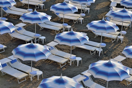 Blue and white umbrellas and sunloungers on empty beachの写真素材
