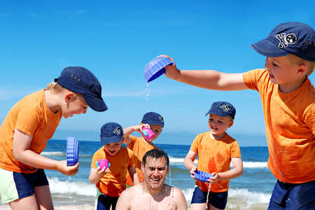 Father and son enjoying time together, playing at the beach, splashing water  Montage photo の写真素材
