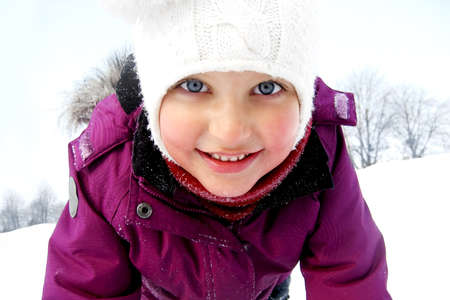 Baby girl having fun in the snow on a winter background の写真素材