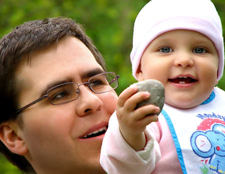 Father looking at his toddler-girl  boasting of found stone  laughing together on an outdoor scenery の写真素材