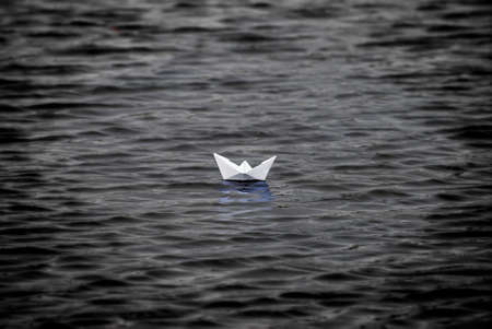 Boat made of paper floating on the dark waterの写真素材