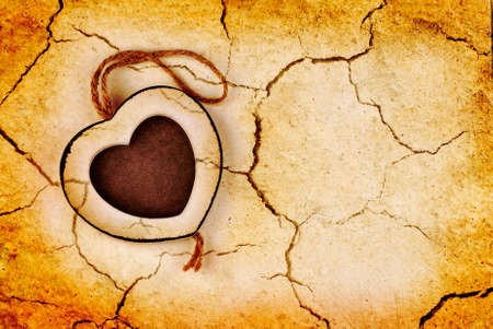 frame in wood heart shape on dry cracked grunge earth の写真素材
