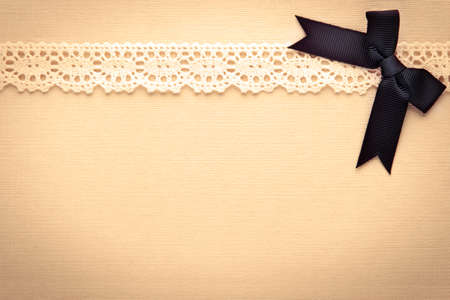 Retro lace and bow over real hand made paper background.の写真素材