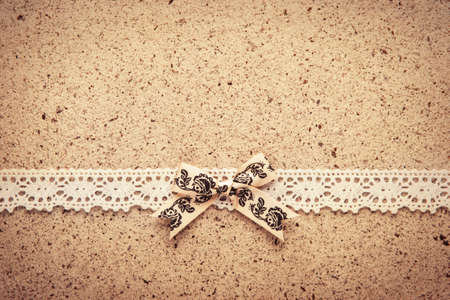 Retro lace and bow over real hand made paper background.の写真素材
