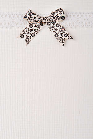 Retro lace and bow over real hand made paper background.の写真素材