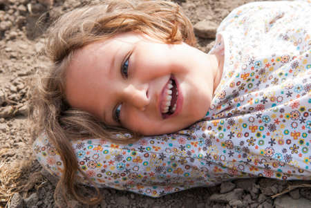 Girl laying on soil and smiling during sunny day.の写真素材
