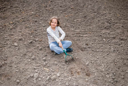 Girl digging in organic soil by hoe.の写真素材