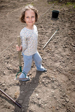Girl standing with hoe during preparation to plant.の写真素材