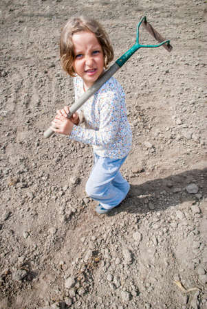 Girl standing with hoe during preparation to plant.の写真素材