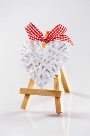 Little tripod wood easel with white rafiia heart and red bow.の写真素材