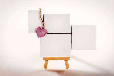 Little tripod wood easel with four white canvas and pink heart.の写真素材