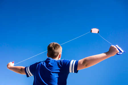 Child flying a kite in the clear blue sky.