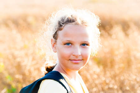 Summer girl with rucksack on sunset background meadow.の写真素材