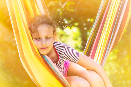 Child girl sleeping in a sunny hammock on vacation.の写真素材