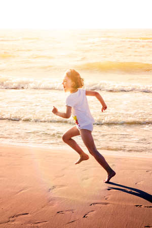 Happy girl running along beach smiling.の写真素材