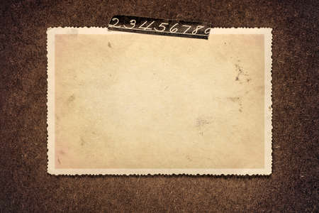 Blank old photo frame for a picture, with decorative torn tape with numbers from photo album page.の写真素材