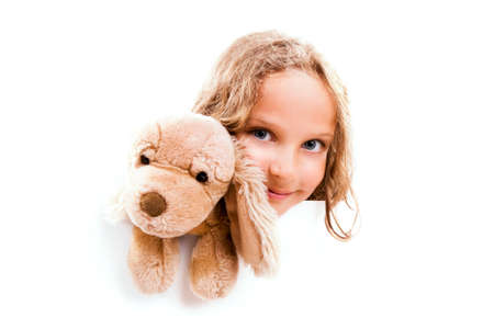 Smiling 7 years old girl with cuddly dog looks out from the empty banner with space for text, isolated on white.の写真素材