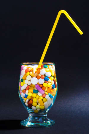 Glass full of colorful pills with straw. Creative composition.の写真素材