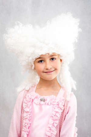 Smiling happy young girl in retro white wigs and princess pink dress.の写真素材