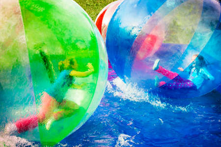 Two young girls playing inside a floating water walking ball.の写真素材