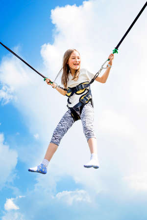 Little girl bouncing high in the air using a bungee trampoline.