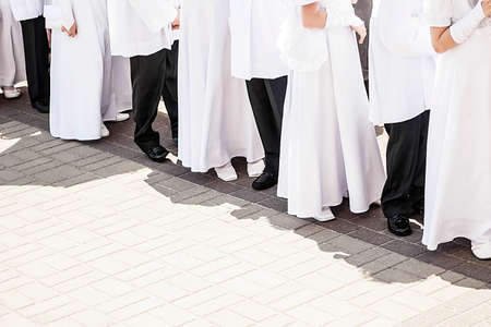 Children in white tunics of first communion waiting for ceremony.