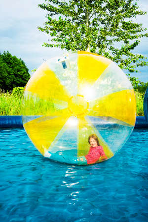 Young girl laying and smiling inside a floating water walking sphere.の写真素材