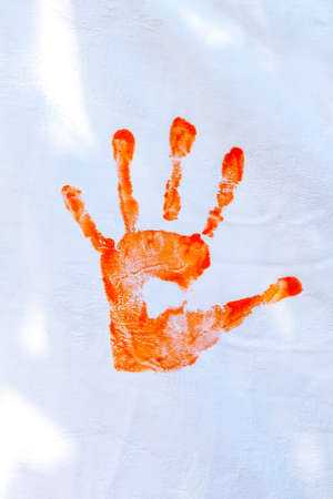 Orange hand paint done by kids on white fabric.