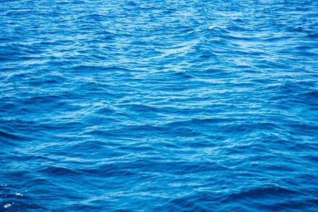 Ocean blue empty water surface background with small waves.