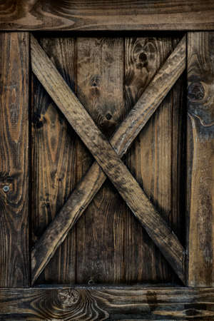 Detail of old wooden door with weathered planks, cross, knots and rings.の写真素材