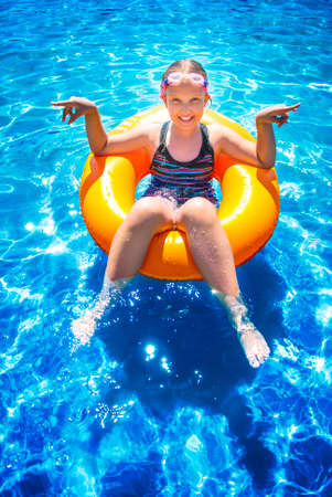 Young girl sitting and smiling in inflatable ring on water ocean. Summer vacations concept.